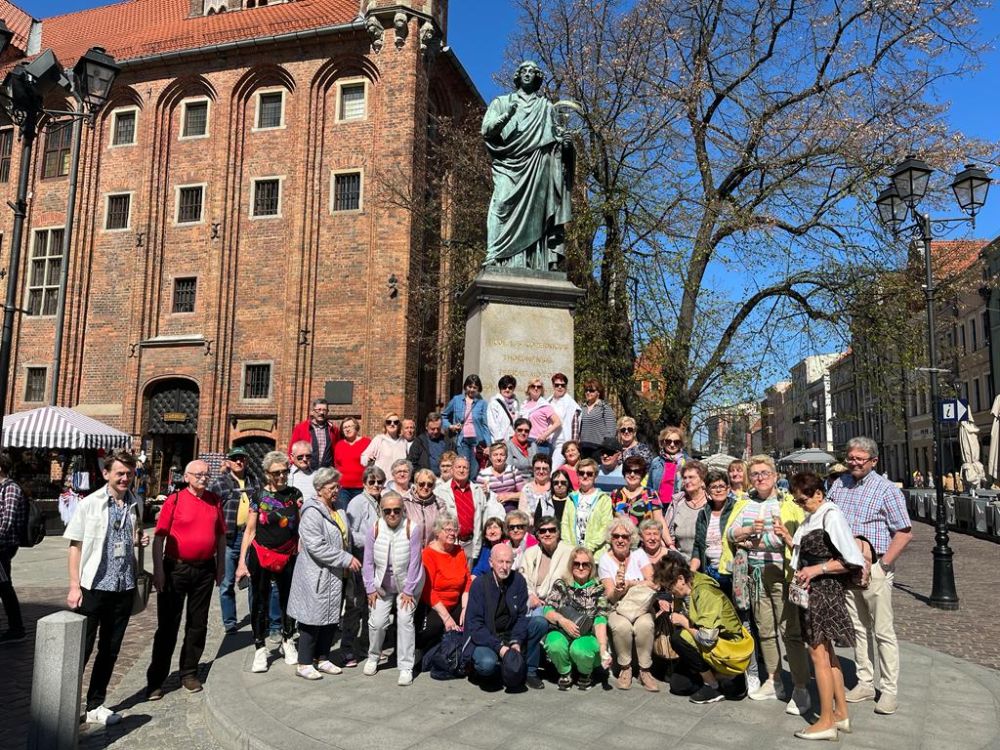  Na trzydniową wycieczkę do Torunia pojechało 49 członków naszego Uniwersytetu. Prognoza pogody na te dni była wspaniała, więc w piątek o godzinie 4 rano mimo, że wczesna pora wyjazdu „zmroziła” nas, wyjechaliśmy z Kamienia w dobrych nastrojach. Po kilku godzinach jazdy zameldowaliśmy się w hotelu Merkury, świetnie położonym w okolicy Starego Miasta. Z sympatycznym przewodnikiem całą grupą pomaszerowaliśmy spacerkiem na spotkanie z historią. W pierwszym dniu zwiedzania mieliśmy okazję zobaczyć zabytkowy budynek toruńskiego Uniwersytetu Mikołaja Kopernika , Krzywą Wieżę – średniowieczną basztę obronną, która jest słynna ze znacznego odchylenia ścian od pionu, spichlerze, Dom Mikołaja Kopernika, Katedrę Świętojańską ze słynną Tuba Dei - olbrzymim 750 kg  dzwonem na wieży. gdzie aby zobaczyć przepiękną panoramę miasta trzeba było wspiąć się po ponad 200 schodach. Niestety dla niektórych z nas było to zbyt duże wyzwanie, ale ci którzy dotarli na samą górę byli zachwyceni. Następnym celem był Zamek Krzyżacki, niestety jeszcze w stanie ruiny. Ciekawym punktem zwiedzana były warsztaty robienia pierników.                      Drugiego dnia spotkaliśmy się na bulwarach toruńskich aby zaokrętować się na stateczku i odbyć rejs po Wiśle oraz obejrzeć miasto od strony rzeki. Jest to jeden z siedmiu cudów  świata – panorama Torunia. Następnie po powrocie na Stare Miasto było obowiązkowe zdjęcie pod pomnikiem Mikołaja Kopernika, obejrzeliśmy z zewnątrz piękny Dwór Artusa, Dom pod Gwiazdą, Piernikową Aleję Gwiazd. Ciekawym też punktem było Planetarium - kosmiczne kino, gdzie półleżąc w wygodnych fotelach mogliśmy dowiedzieć  się dużo o zorzy polarnej i sposobie jej tworzenia się. Trzeci dzień pobytu w pięknym , historycznym Toruniu był dniem powrotu do Kamienia, ale po drodze, przy nadal przepięknej słonecznej pogodzie, zatrzymaliśmy się w Ciechocinku na dwugodzinny spacer po słynnym uzdrowiskowym mieście. Oczywiście obowiązkowym punktem były słynne Tężnie, Fontanna Grzybek i Muszla Koncertowa w Parku Zdrojowym.